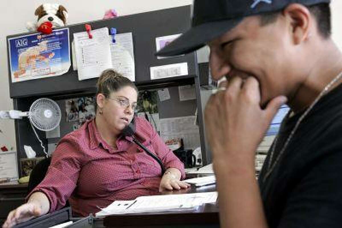 Ayesha Tully, left, responds to call while Larryll Emerson waits for information pertaining to his next work assignment, in this file photo from July 26, 2005, at the Staffmark temp agency in Cypress, Calif. (AP Photo/Ric Francis)