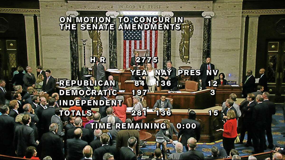 In this image from House Television, with partial voting totals on the screen, a woman, at the rostrum just below the House presiding officer, seen between the "yea" and "nay" wording, is removed from the House chamber after she began shouting during the vote for the bill to end the partial 16-day government shutdown and to fund the government. The woman was described by lawmakers and aides as a long-time House stenographer. (AP Photo/House TV)