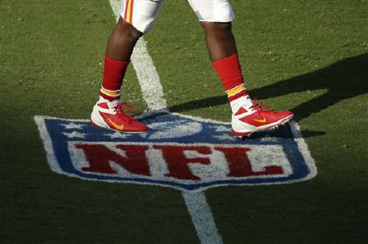 A player for the Kansas City Chiefs walks across an NFL logo before a preseason NFL football game against the San Francisco 49ers Friday, Aug. 16, 2013, in Kansas City, Mo. (AP Photo/Charlie Riedel)