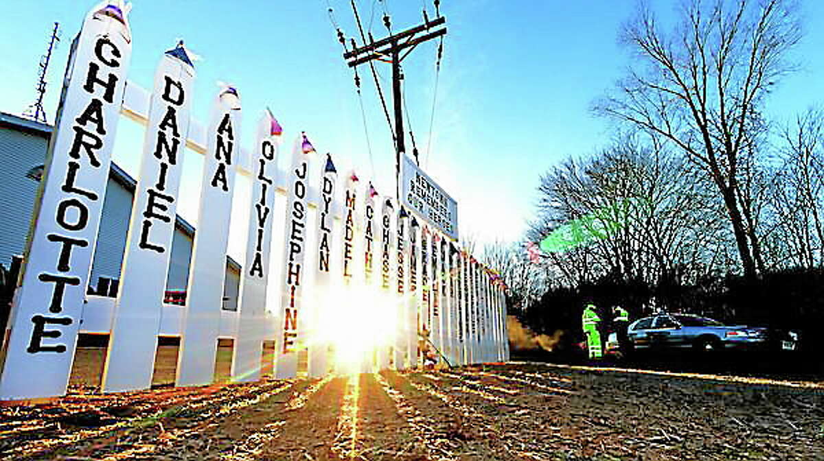 Staff photos by Tom Kelly IVThe memorial setup near the Sandy Hook firehouse, and the entrance road to Sandy Hook Elementary School continues to grow as seen here early Thursday morning December 20, 2012. The sun rises above the trees, illuminating parts of the memorial, as Connecticut State Troopers block of the entrance road to the Sandy Hook Elementary School.