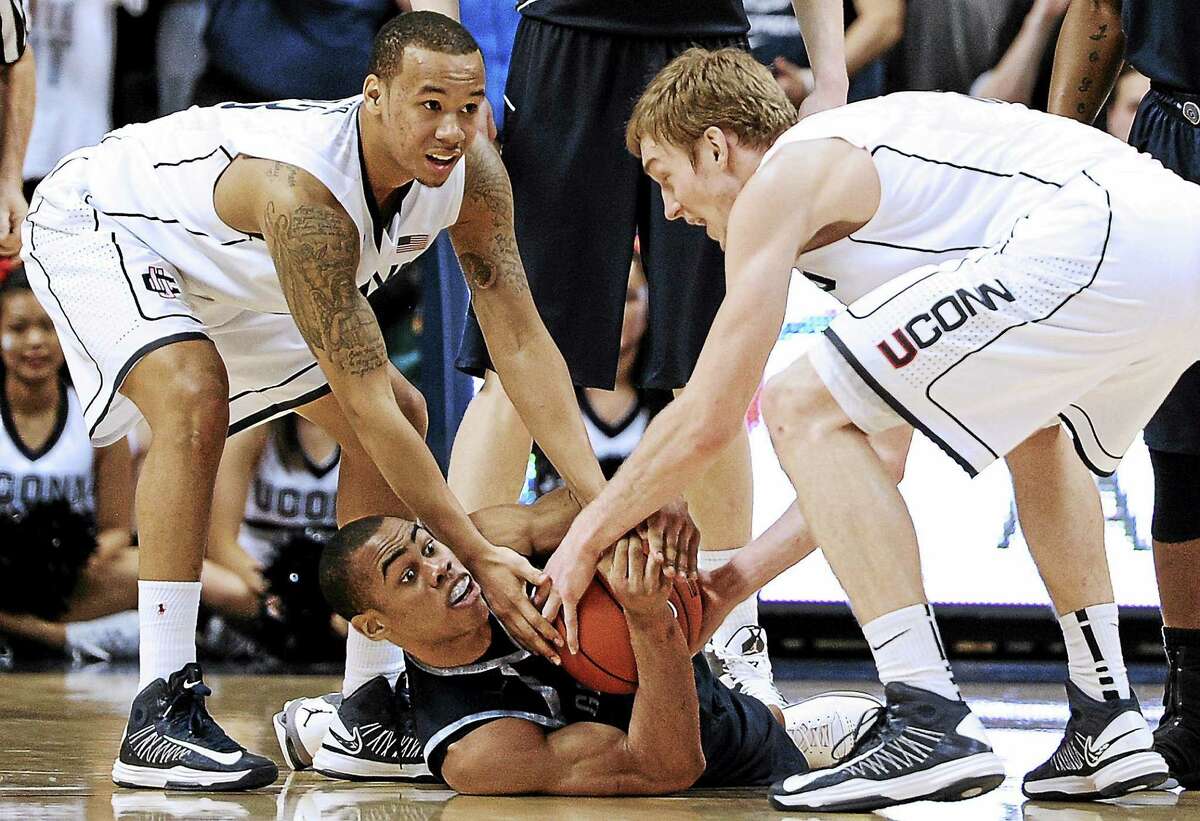 UConn’s Shabazz Napier and Niels Giffey, right, reach for the ball from Georgetown’s Markel Starks during the first overtime of the Hoyas’ 79-78 double-OT win in Storrs on Feb. 27, 2013.