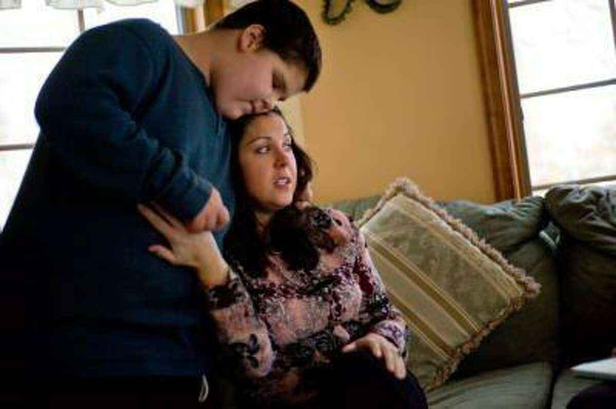 Christian Goff, 12, pauses to give his mother, Kim Goff, a spontaneous hug as she talks about the challenges facing her family. (THE EVENING SUN/Clare Becker)