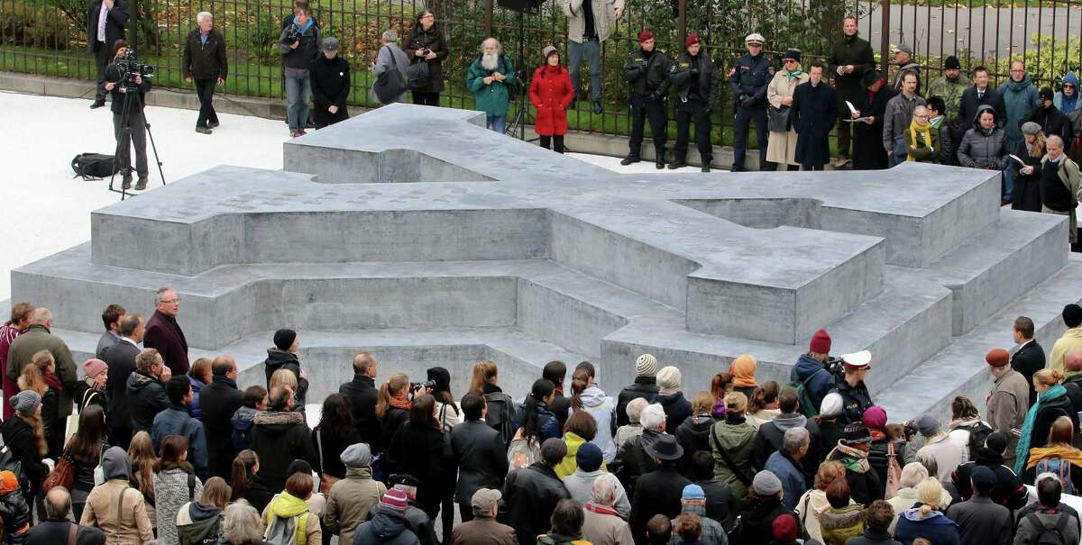 People surround a memorial dedicated to deserters of the Nazi Wehrmacht troops and victims of their military justice during its unveiling ceremony in downtown Vienna, Austria, Friday, Oct. 24, 2014. The memorial is located in front of the presidential office in the Hofburg palace and the federal chancellery. (AP Photo/Ronald Zak)