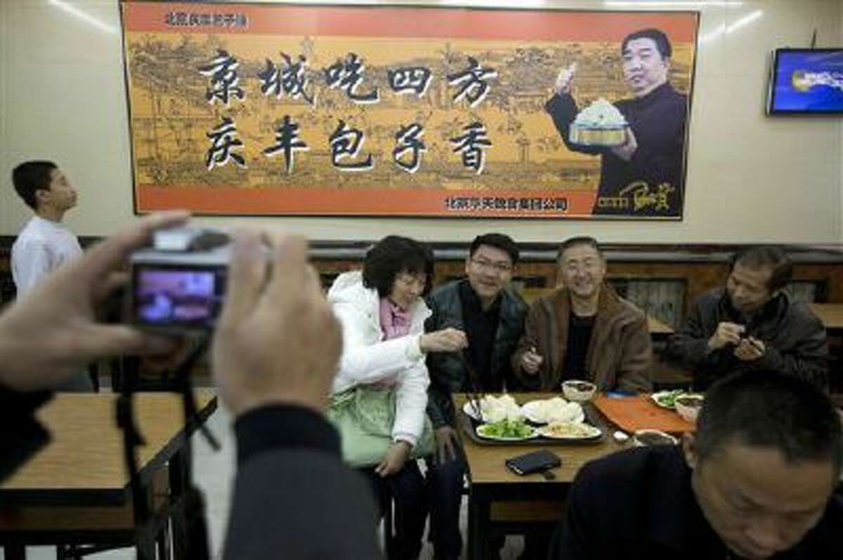 Tourists from Guangdong province, who ordered similar food to what Chinese President Xi Jinping ate the day before, pose for photos at the Qing-Feng Steamed Dumpling Shop in Beijing, China.