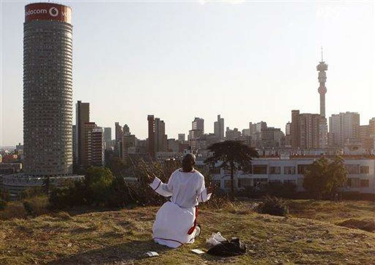 A worshipper offers weekend prayers as vraious church groups offered weekend prayers for former president Nelson Mandela on a hill overlooking the city in Johannesburg, Saturday, June 8, 2013. Mandela is in "serious but stable" condition after being taken to a hospital to be treated for a lung infection, the government said, prompting an outpouring of concern from admirers of a man who helped to end white racist rule. (AP Photo/Denis Farrell)