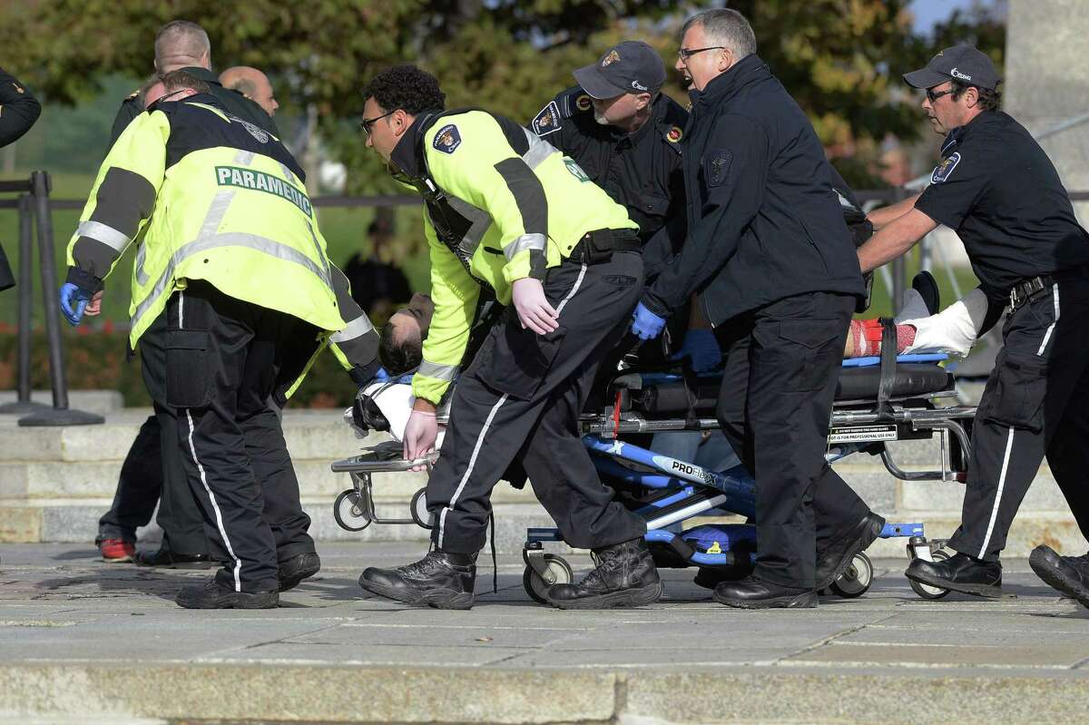 Paramedics and police pull a victim away from the Canadian War Memorial in Ottawa on Wednesday Oct. 22, 2014. A soldier standing guard at the National War Memorial in Ottawa has been shot by an unknown gunman and people report hearing gunfire inside the halls of Parliament.
