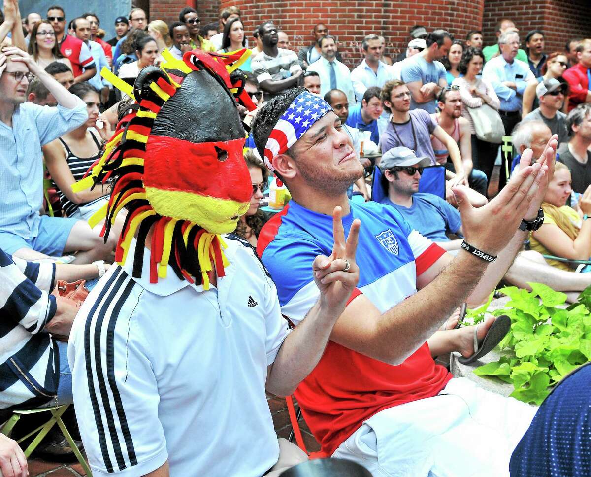 (Arnold Gold-New Haven Register) Jason Wright (left), born in Germany and living in New Haven, and Clayton Banks (center) of Derby watch Germany play the USA in a World Cup soccer match on 6/26/2014 with other fans in Pitkin Plaza in New Haven.