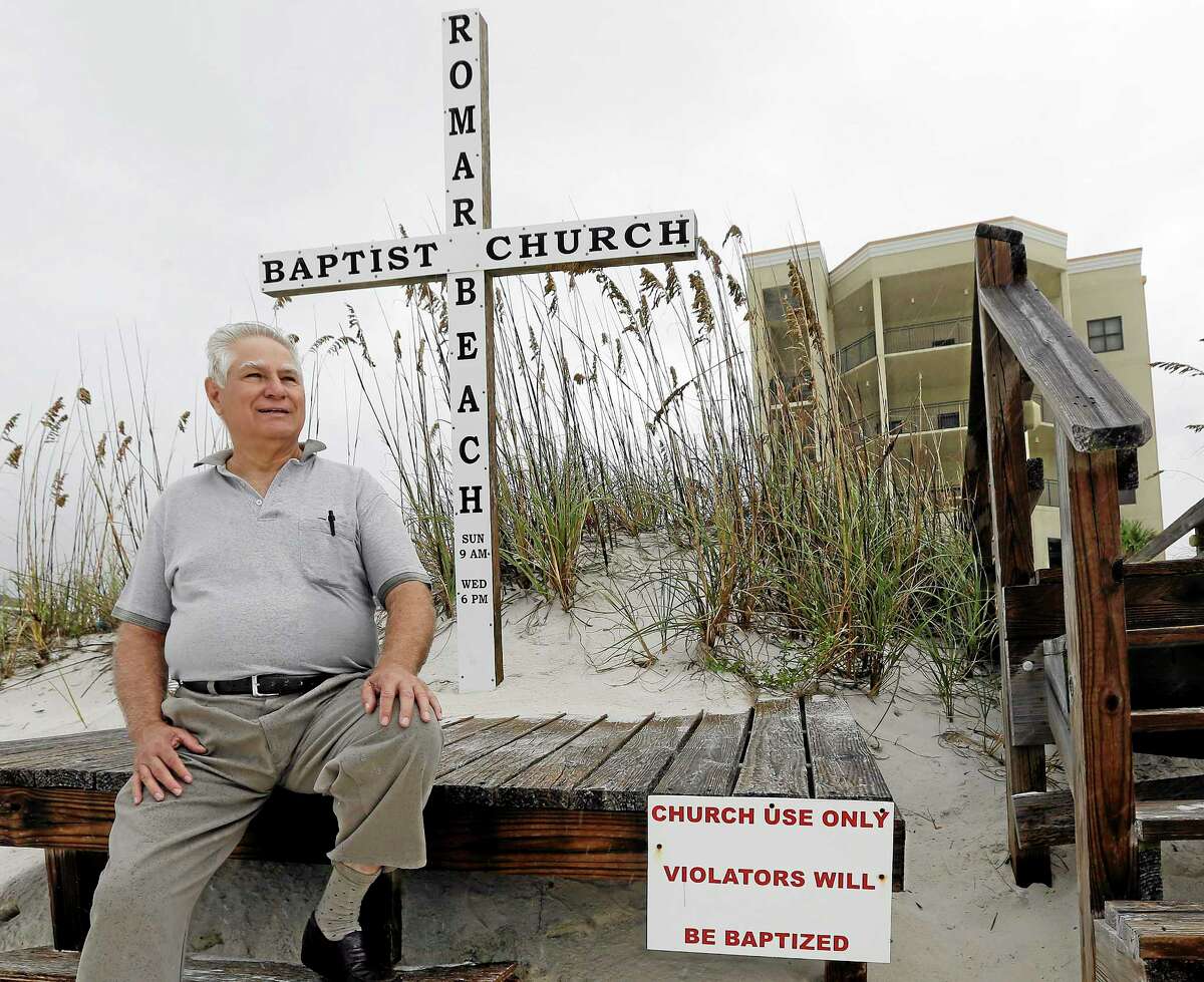 Romar Beach Baptist Church Pastor Paul Smith sits on a platform that holds a cross at the end of the boardwalk leading to the beach in Orange Beach, Ala., Sunday, Oct. 6, 2013. The hurricane proof church built welcomes all and provides shelter for it's members and others in need when storms threaten the coast. (AP Photo/Dave Martin)