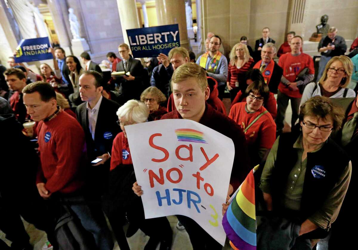 In this Jan. 13, 2014 file photo, Dylan Hutson, center, of Indianapolis, holds a sign voicing his opposition to a measure amending the state’s constitution to ban gay marriage at the Statehouse in Indianapolis. A federal judge struck down Indiana’s ban on gay marriage Wednesday, calling it unconstitutional.