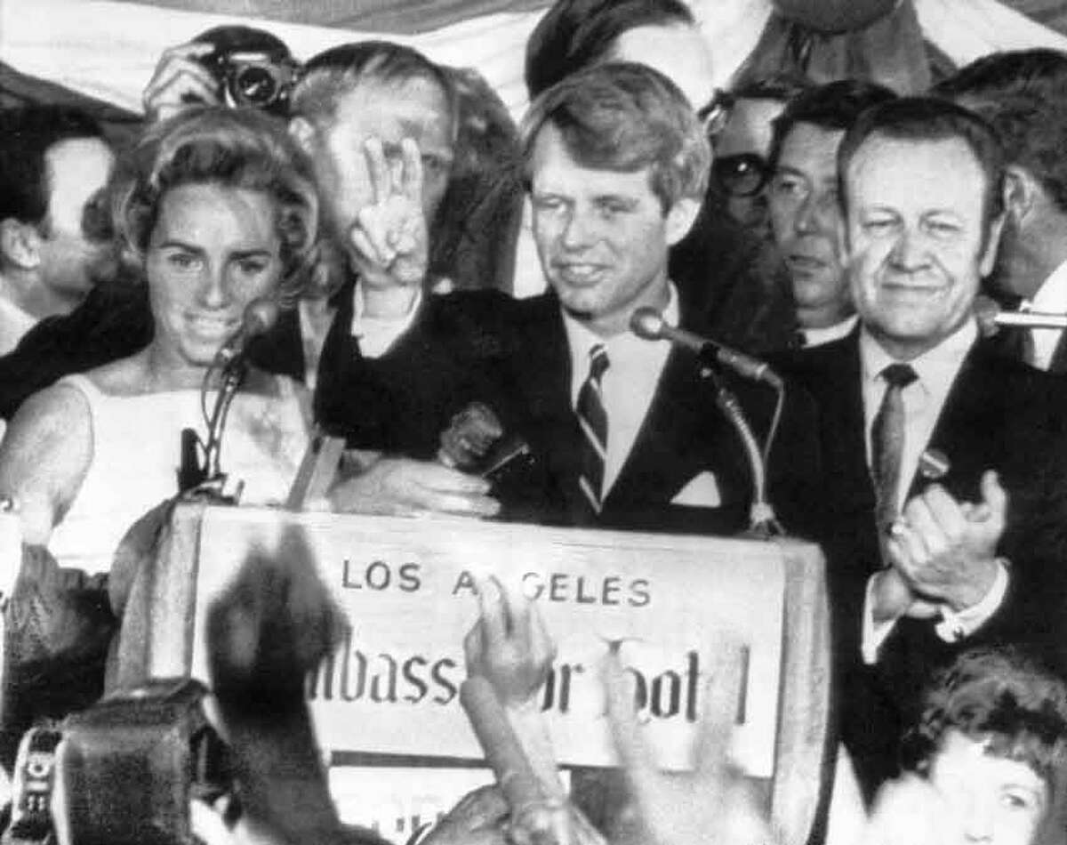 U.S. Sen. Robert F. Kennedy holds two fingers up in a victory sign as he talks to campaign workers at the Ambassador Hotel in Los Angeles, Ca., June 5, 1968. He is flanked by his wife Ethel, left, and his California campaign manager, Jesse Unruh, speaker of the California Assembly. After making the speech, Kennedy left the platform and was assassinated in an adjacent room. (AP Photo)