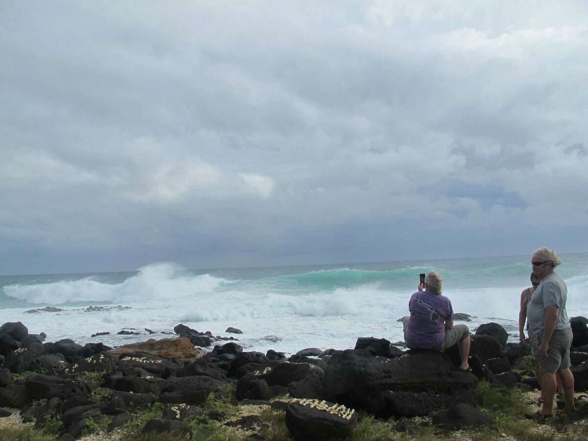 People watch high surf at South Point, Hawaii on Friday, Oct. 17, 2014 as Hurricane Ana carved a path just south of the island state. The storm prompted a flood advisory and winds strong enough for officials to urge caution. (AP Photo/Audrey McAvoy)