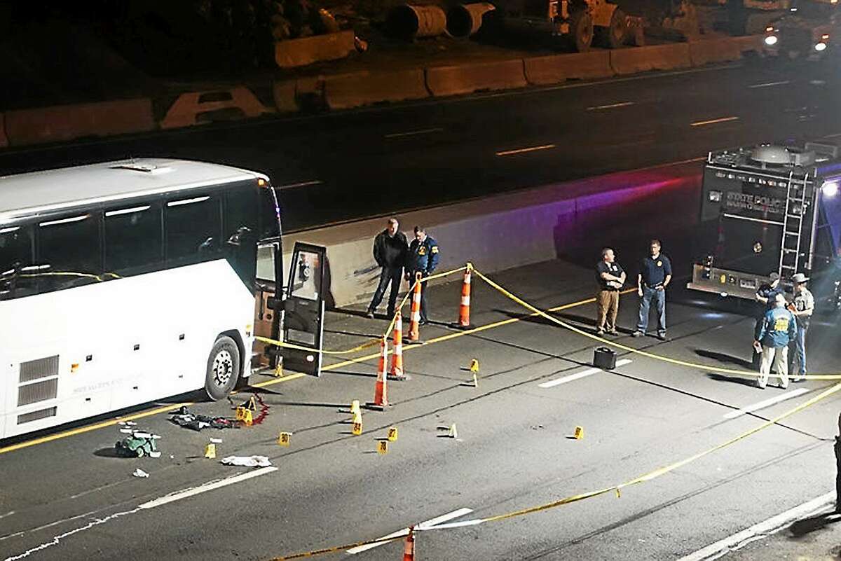 Law enforcement investigate the scene of a stabbing aboard a tour bus late Tuesday, Oct. 14, 2014 in Norwalk, Conn. A man who stabbed passengers on the casino-bound tour bus on Interstate 95 was fatally shot by state police, officials said.