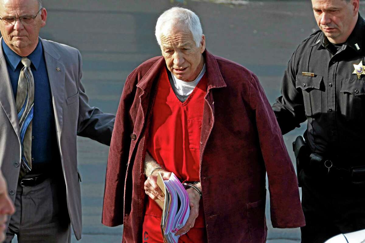 FILE - In this Jan. 10, 2013 file photo, former Penn State University assistant football coach Jerry Sandusky, center, leaves the Centre County Courthouse after attending a post-sentence motion hearing in Bellefonte, Pa. Sandusky is expected to participate in the proceeding to have his Penn State pension restored by video conference. The proceeding begins on Tuesday, Jan. 7, 2014. Sandusky lost a $4,900-a-month pension in October 2012, when he was sentenced to 30 to 60 years in prison for child sexual abuse. (AP Photo/Gene J. Puskar, File)