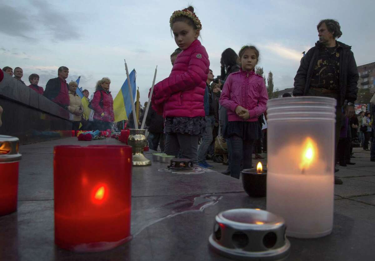 Children look at candles during a rally in memory of civilians killed in the town of Mariupol, eastern Ukraine Wednesday, Oct. 15, 2014. Local authorities in Mariupol, a government-controlled city on the Black Sea, said seven civilians were killed and 17 injured Tuesday by shelling in the nearby village of Sartana. (AP Photo/Dmitry Lovetsky)