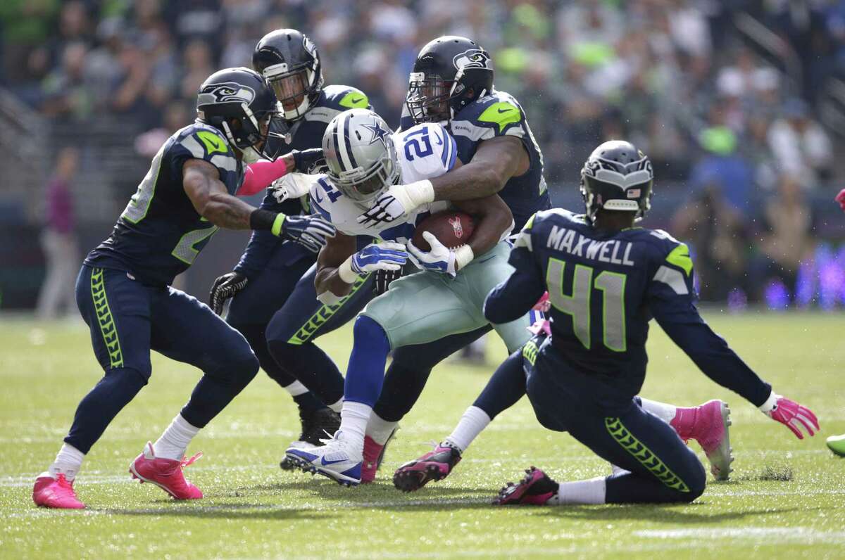 Dallas Cowboys running back Joseph Randle is tackled by a gang of Seahawks defenders in the first half of Sunday’s game in Seattle.