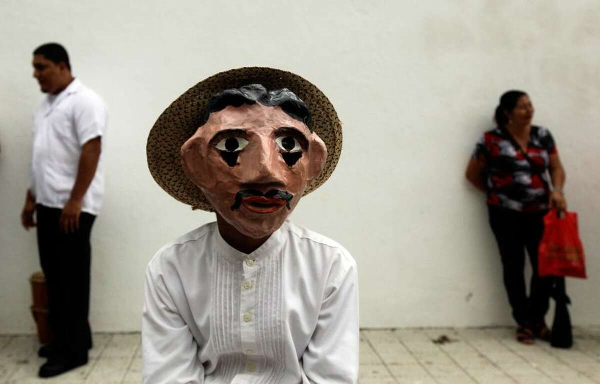 A boy wearing traditional mask and costume, representing a farmer, attends Corpus Christi celebrations in the streets of La Villa, Panama, Thursday, May 30, 2013. Residents don colorful masks and bright costumes as they dance through the streets of this small Panamanian town, for its annual commemoration of Corpus Christi, a Roman Catholic holiday celebrating the transformation of the body and blood of Christ into bread and wine. (AP Photo/Arnulfo Franco)