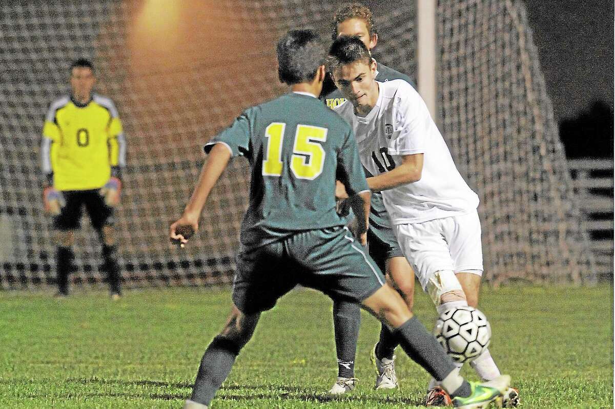 Laurie Gaboardi Register Citizen Torrington's Amar Suljic passes the ball past Holy Cross defender, Alex Matos in the Red Raiders 3-1 win against the Crusaders. Suljic scored the first goal of the game.
