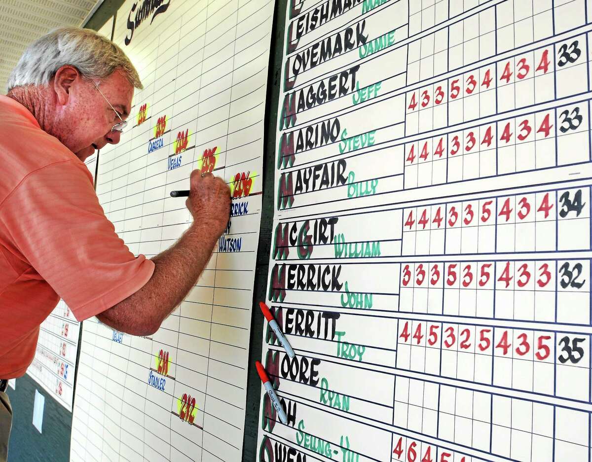 Calligrapher Dave Koenig writes the scores for each and every player at the Travelers Championship on a giant scoreboard near the 18th green.