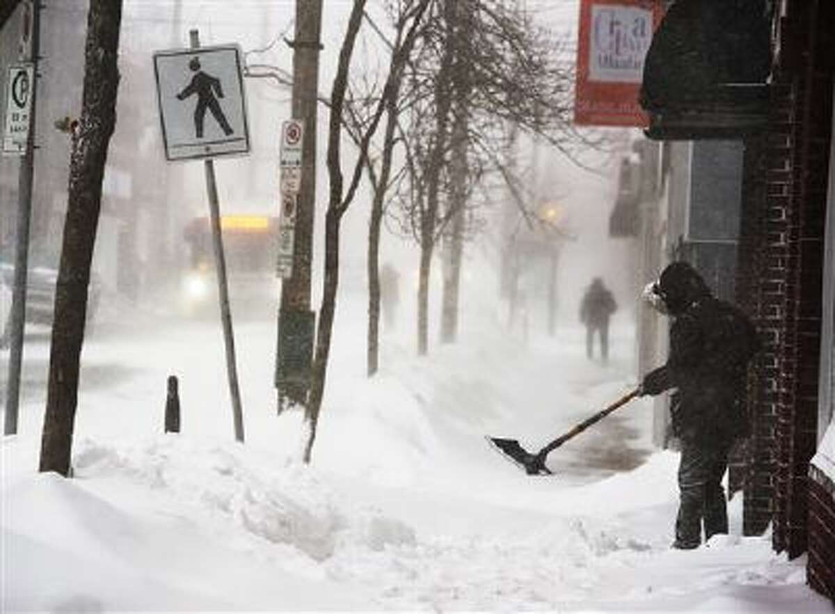 A man clears a sidewalk Friday in blizzard conditions in Halifax, Nova Scotia.