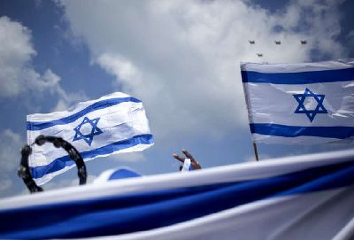 An African migrant worker holds Israeli flags during Independence Day in Tel Aviv, Tuesday, April 16, 2013.