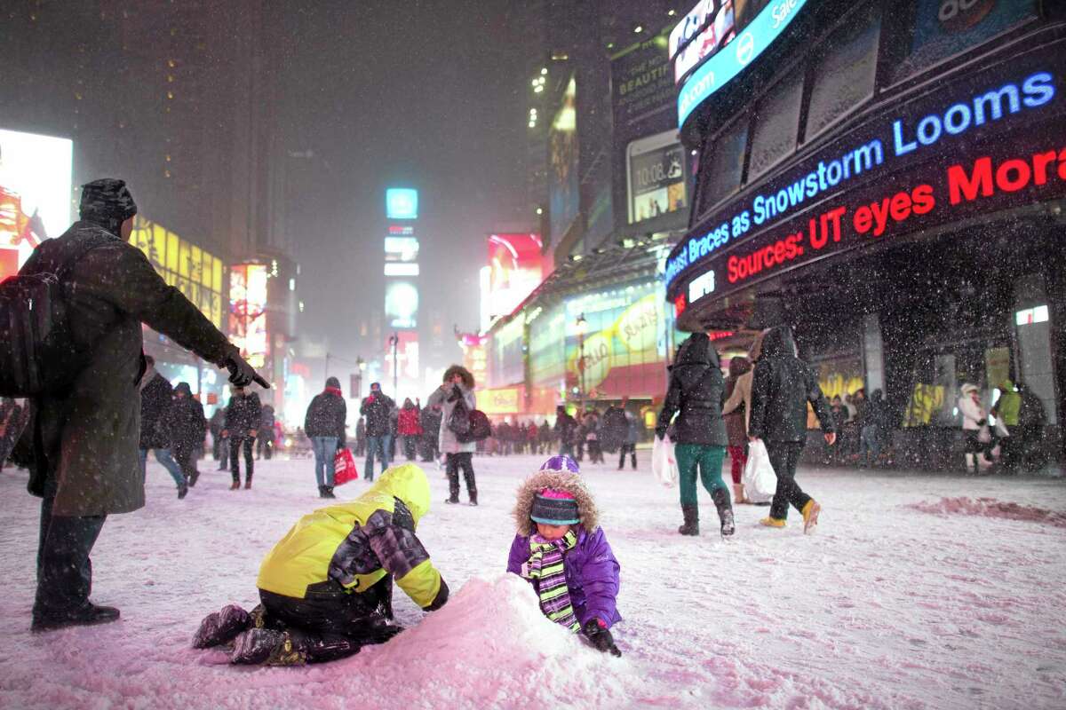 Children make a snow pile in Times Square, during a snowstorm, Thursday, Jan. 2, 2014, in New York. The storm is expected to bring snow, stiff winds and punishing cold into the Northeast. (AP Photo/John Minchillo)