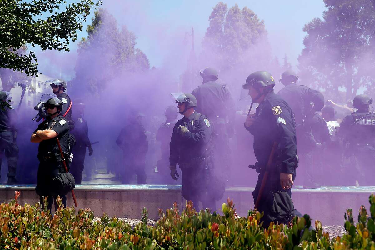 Berkeley Police stand guard as a smoke bomb is set off at Civic Center Park in Berkeley, Calif. on Sunday, August 27, 2017.