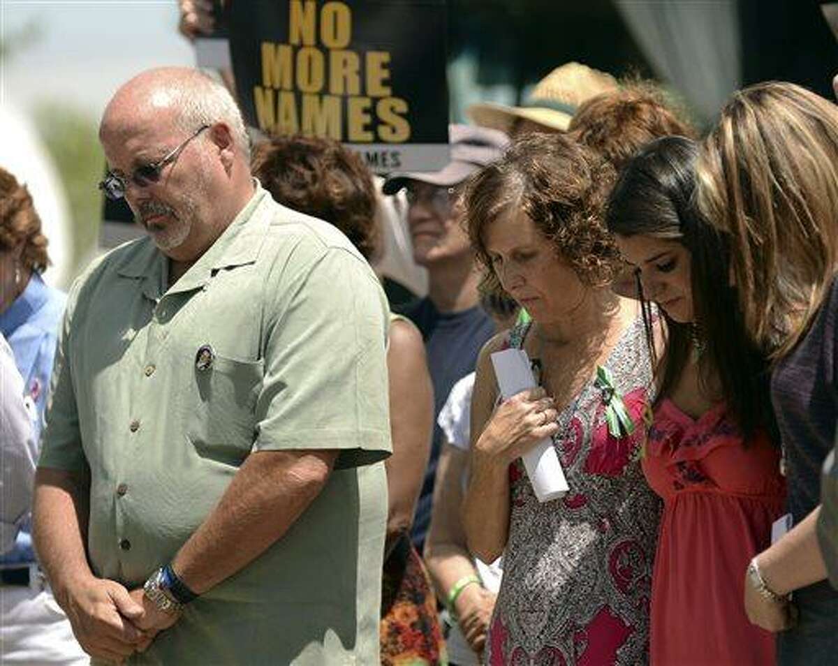 From left, Tom Sullivan, father of Aurora shooting victim Alex; Jane Dougherty, sister of Sandy Hook elementary school shooting victim Mary Sherlach; Carlee Soto, sister of Sandy Hook elementary school shooting victim Victoria; and Coni Sanders, daughter of Columbine High School shooting victim Dave Sanders, stand together during an event to honor those killed in the massacre at an Aurora, Colo. movie theater a year after the attack on Friday, July 19, 2013, in Arapahoe County, Colo. The vigil participants read a list of names of those killed in gun violence across the nation since the elementary school shooting rampage in Newtown, Conn., in December. (AP Photo/The Denver Post, Hyoung Chang)