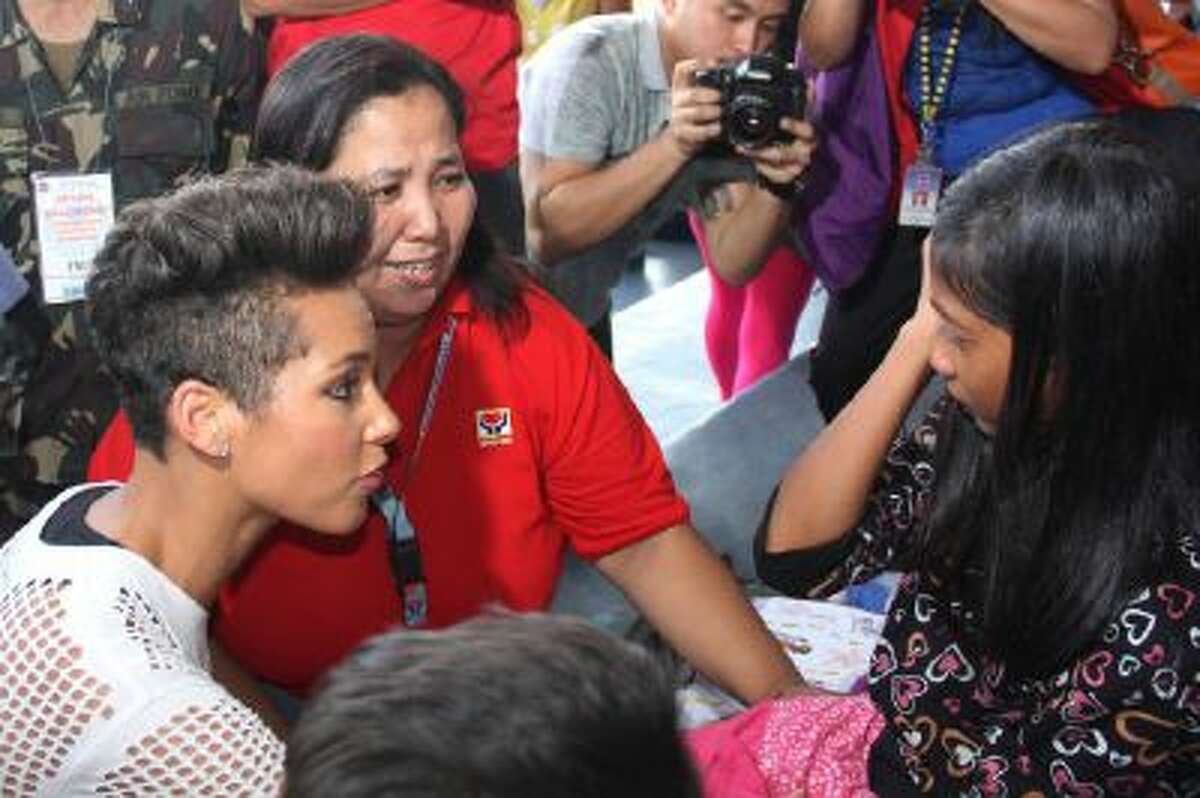 In this photo released by the Philippine Air Force, Grammy-winning singer Alicia Keys, left, talks to a typhoon survivor as she visits the Villamor Air Base in suburban Pasay, south of Manila, Philippines, Monday Nov. 25, 2013. Keys visited the air force base to bring cheer to hundreds of evacuees from eastern Philippine provinces wracked by Typhoon Haiyan earlier this month.