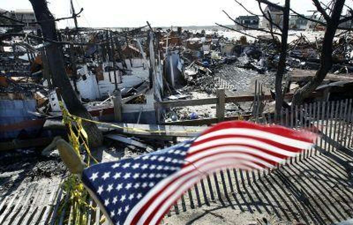 Flags decorate a fence Thursday, April 25, 2013, in Brick, N.J., around the burned remains of more than 60 small bungalows at Camp Osborn which were destroyed last October during Superstorm Sandy. Six months after Sandy devastated the Jersey shore and New York City and pounded coastal areas of New England, the region is dealing with a slow and frustrating, yet often hopeful, recovery. (AP Photo/Mel Evans)
