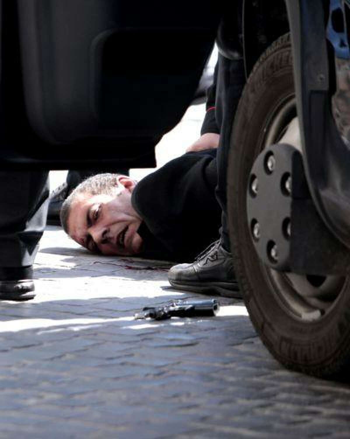 A man believed to be the assailant lies on the ground detained by police after a shootout outside the Chigi Premier's office, in Rome, Sunday, April 28, 2013. Reports say two paramilitary police officers were shot and wounded outside the Italian premier's office as the new leader Enrico Letta was sworn in about a kilometer (half-mile) away. It was unclear if there was any connection between the events. (AP Photo/Mauro Scrobogna, Lapresse) ITALY OUT