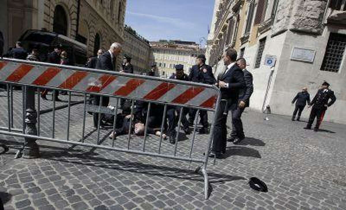 A wounded Carabinieri paramilitary police officer lies on the ground after being shot outside the Chigi Premier's office, in Rome, Sunday, April 28, 2013. Two paramilitary police officers were shot and wounded Sunday in a crowded square outside the Italian premier's office as the new leader Enrico Letta was sworn in about a kilometer (half-mile) away. It was unclear if there was any connection between the events. (AP Photo/Gregorio Borgia)