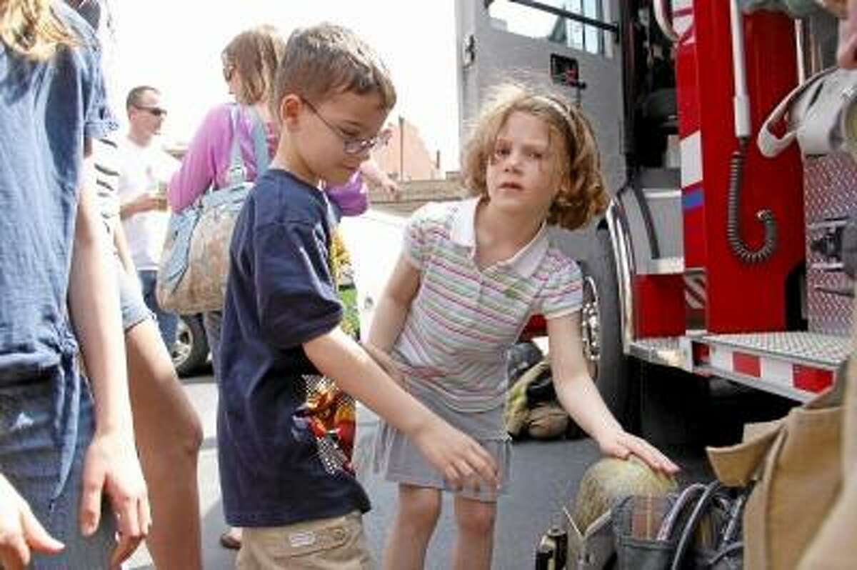 Siblings Sam and Savannah Ormezzano touch some fire equipment during a fire safety demonstration by the Torrington Fire Department at KidsPlay in Torrington on Sunday. About 30 people showed up the event held in the afternoon. ESTEBAN L. HERNANDEZ/REGISTER CITIZEN