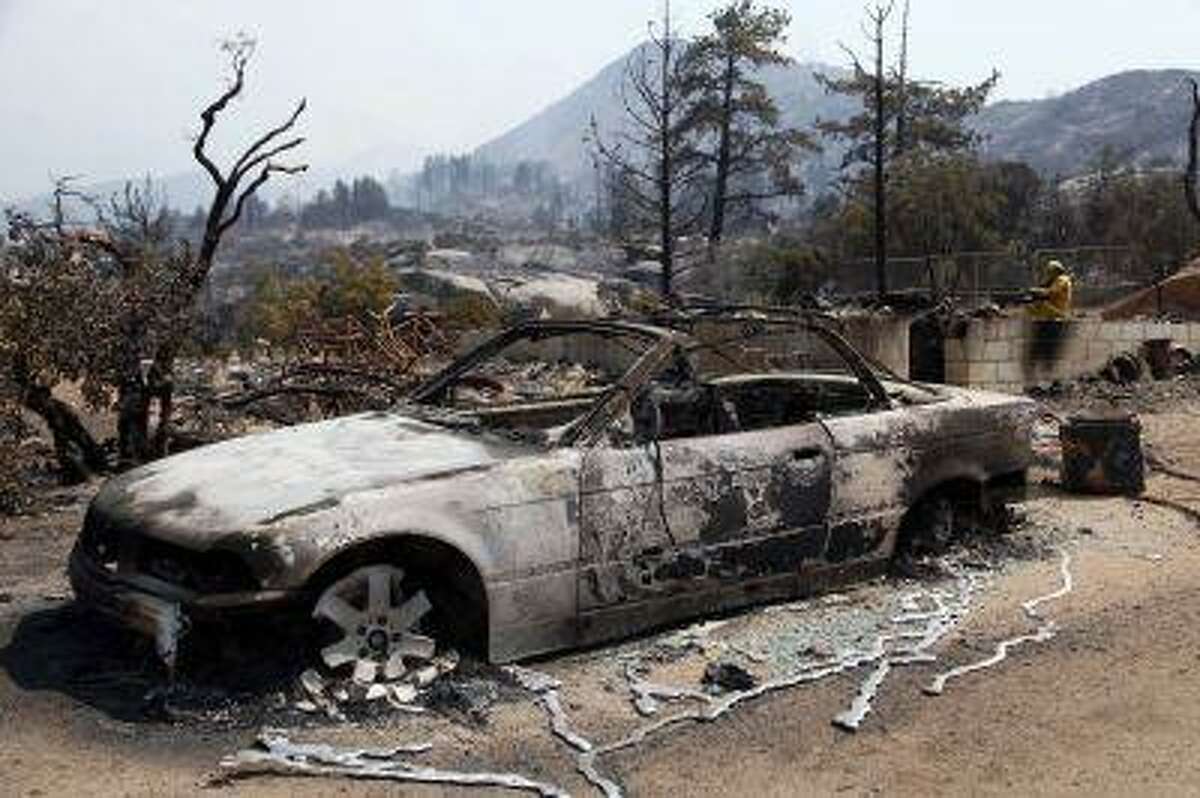 The charred remains of a car are shown after a wildfire passed through the area, Thursday July 18, 2013 in Lake Hemet, Calif.