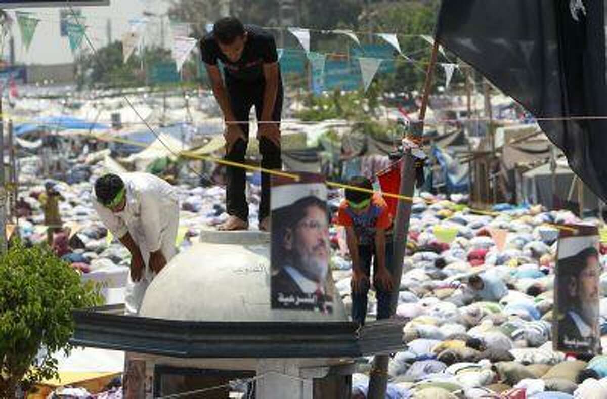 Supporters of deposed Egyptian President Mohamed Mursi perform Friday prayers as they stand on top of a structure during a protest at the Rabaa Adawiya square where they are camping at in Cairo July 19, 2013.