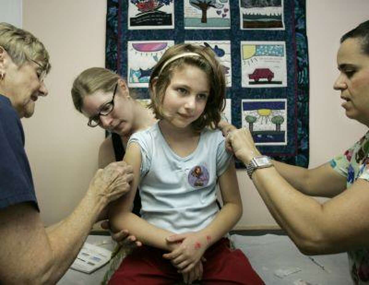 Nurses Gay Ohlrich, left, and Edie Goldberg, right, double-up to give inoculations to Ava Burka, 6, as her mother, Kristin Burka, comforts her daughter with a reassuring embrace, in the office of Dr. Howard Bennett, a kid-friendly pediatrician, in Washington, Oct. 19, 2006. Dr. Bennett uses these techniques to calm anxious young patients when getting their shots. (AP Photo/J. Scott Applewhite)