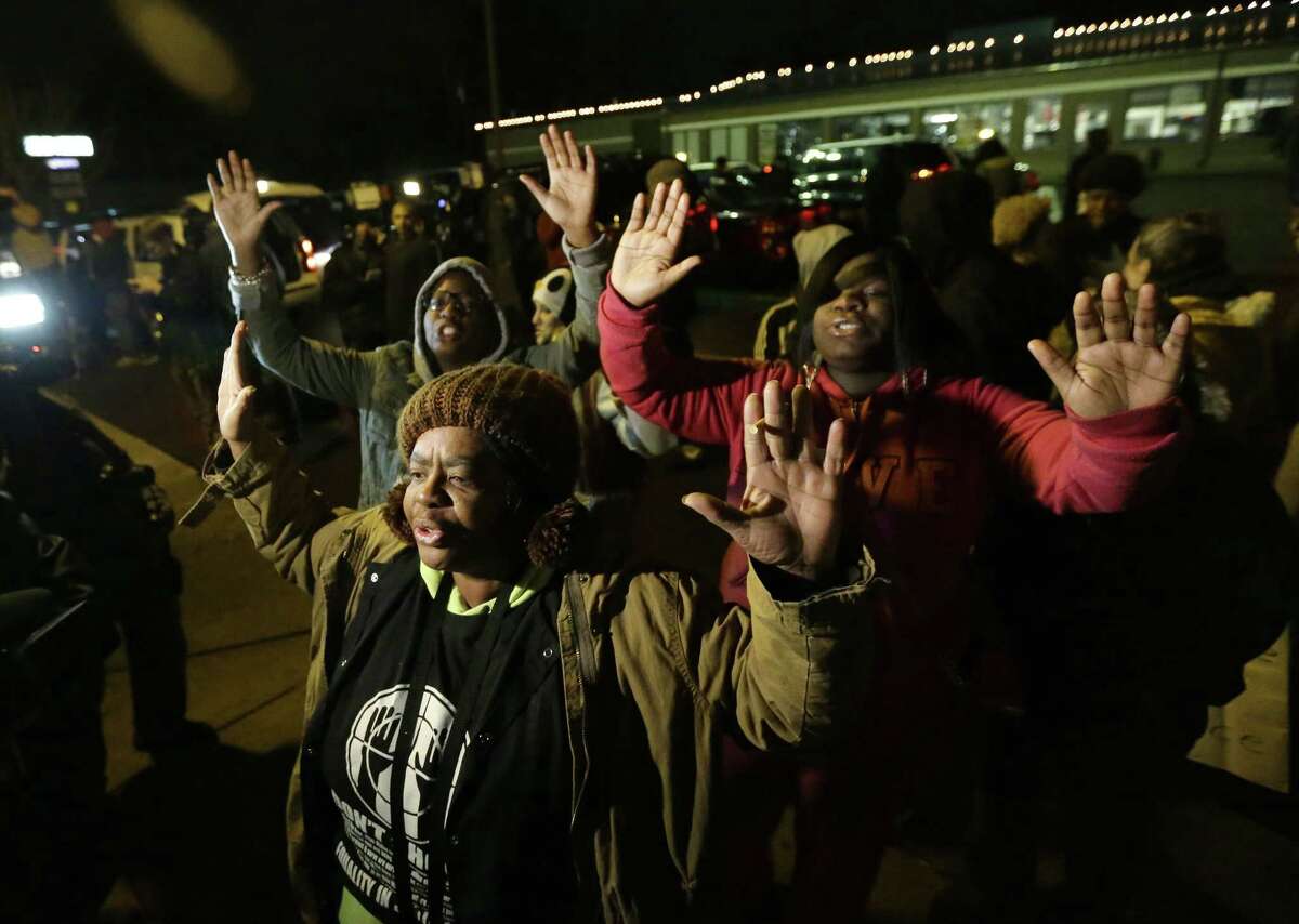Barbara Jones, joined by other protesters, raises her hands, Monday, Nov. 24, 2014, in Ferguson, Mo., more than three months after an unarmed black 18-year-old man was shot and killed there by a white policeman in Ferguson. Ferguson and the St. Louis region are on edge in anticipation of the announcement by a grand jury whether to criminally charge Officer Darren Wilson in the killing of Michael Brown.