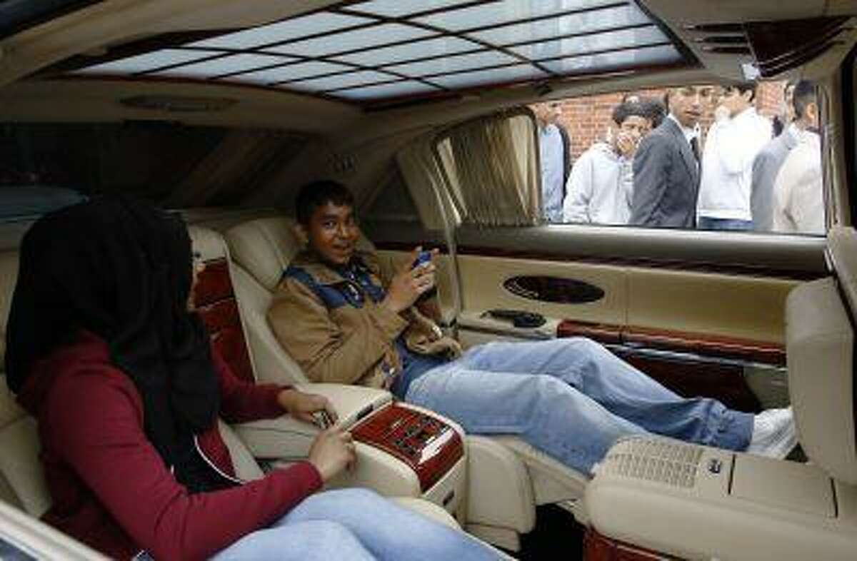 School friends Jannat and Wahid sit in a Maybach hired to take part in a parade of "supercars" during Morpeth School graduation day in Tower Hamlets, eastLondon June 21, 2013. REUTERS/Olivia Harris