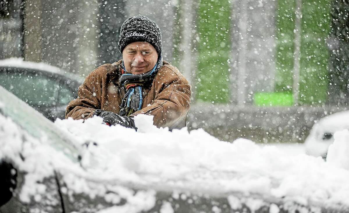 Curt Anderson clears snow from his vehicle in downtown Austin, Minn., Thursday.