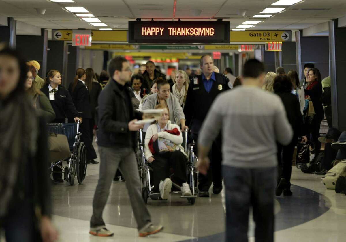 FILE - In this Nov. 26, 2013, file photo, travelers walk under a sign reading “Happy Thanksgiving” at LaGuardia Airport in New York. There will be 12.3 million roundtrip passengers, globally, on U.S. airlines during the 2014 holiday travel period, up 1.5 percent from 2013, according to the industryís lobbying group, Airlines for America.