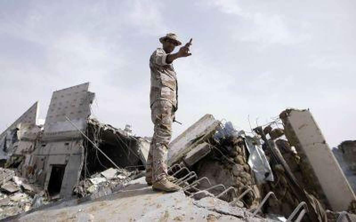 Libyan soldier stand on top of a destroyed building at the Bab Al-Aziziya district where veteran leader Moamer Kadhafi has his base, in Tripoli on June 7, 2011 as NATO warplanes pounded the Libyan capital.