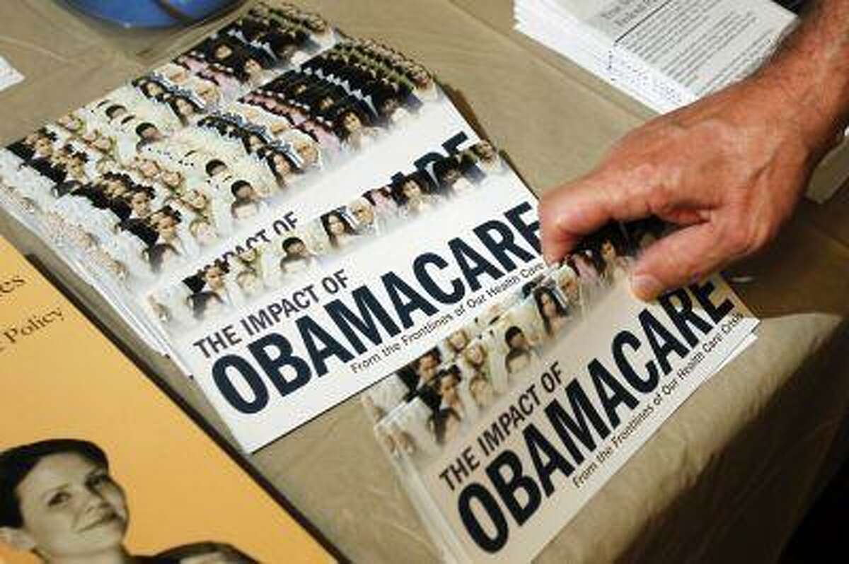 A Tea Party member reaches for a pamphlet titled "The Impact of Obamacare", at a "Food for Free Minds Tea Party Rally" in Littleton, New Hampshire in this October 27, 2012 file photo. The Obama administration said on July 2, 2013 it would not require employers to provide health insurance for their workers until 2015, delaying a key provision of President Barack Obama's healthcare reform law by a year, to beyond the next election. REUTERS/Jessica Rinaldi//Files (UNITED STATES - Tags: POLITICS HEALTH)