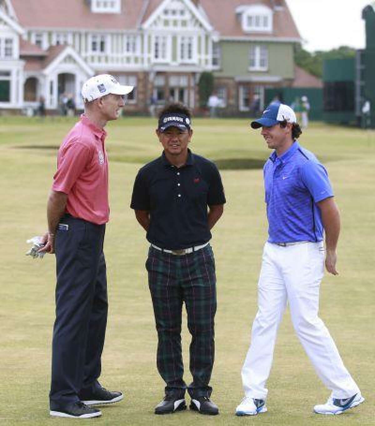 Jim Furyk of the United States, left, Hiroyuki Fujita of Japan, center, and Rory McIlroy of Northern Ireland pose for a photo in front of the club house after a practice round ahead of the British Open Golf Championship at Muirfield, Scotland, Wednesday July 17, 2013.