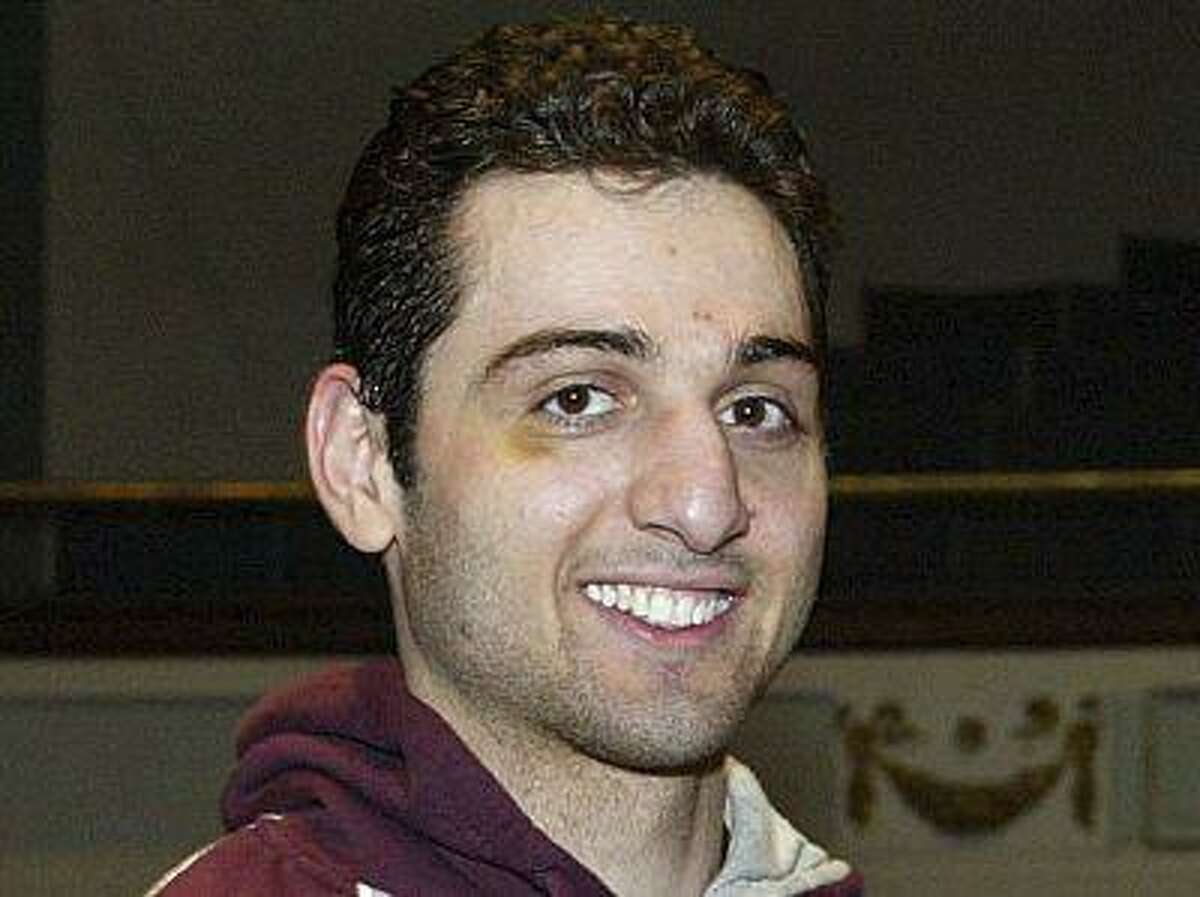 In this Feb. 17, 2010, photo, Tamerlan Tsarnaev, left, Smiles after acceping the trophy for winning the 2010 New England Golden Gloves Championship from Dr. Joseph Downes, right, in Lowell, Mass. Tsarnaev, 26, who had been known to the FBI as Suspect No. 1 in the Boston Marathon Explosions and was seen in surveillance footage in a black baseball cap, was killed overnight on Friday, April 19, 2013, officials said. (AP Photo/The Lowell Sun, Julia Malakie)
