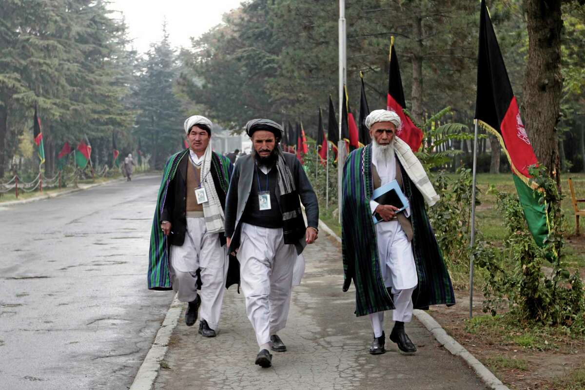Afghan delegates walk on the street on the second day of the Loya Jirga, or the consultative council in Kabul, Afghanistan, Friday, Nov. 22, 2013. Representatives from different groups gather in separate rooms and discuss until meeting again in the council. President Hamid Karzai urged tribal elders Thursday to approve a security pact with Washington that could keep thousands of U.S. troops in Afghanistan until 2024, but he added a wrinkle that he prefers his successor sign the document after elections next April. (AP Photo/Rahmat Gul)