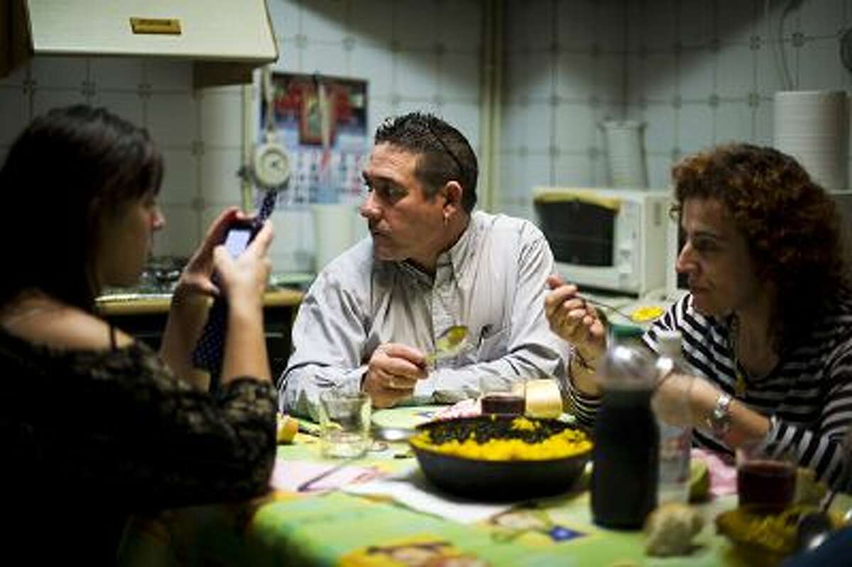 VILLACANAS, SPAIN - NOVEMBER 23: Forty-eight year old former door factory worker Angel Perez Fernandez (C) eats Paella together with his forty-year old wife, Maria Regine Bueno Villar (R), who worked as a cleaning lady at door factories, and their unemployed twenty-year daughter Maria Regina, at the home of his mother in law on November 23, 2012 in Villacanas, Spain. During the boom years, where in its peak Spain built some 800,000 houses a year accompanied by the manufacturing of millions of wooden doors where needed, the people of Villacanas were part of Spain's middle class enjoying high wages and permanent jobs. During the construction boom years the majority of the doors used within these new developments were made in this small industrial town. Approximately seven million doors a year were once assembled here and the factory employed a workforce of almost 5700 people, but the town is now left almost desolate with the Villacanas industrial park now empty and redundant. With Spain in the grip of recession and the housing bubble burst, Villacanas is typical of many former buoyant industrial Spanish towns now struggling with huge unemployment problems. (Photo by Jasper Juinen/Getty Images)