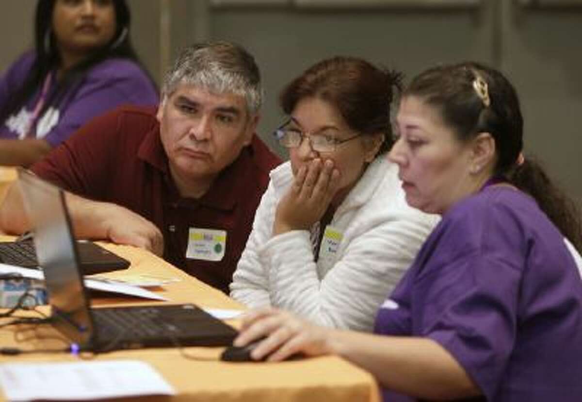 Carlos Barajas, left, and his wife, Martha, center, look over their health insurance plan options with volunteer Elizabeth Lira, at a health fair in Sacramento, Calif. in November 2013.
