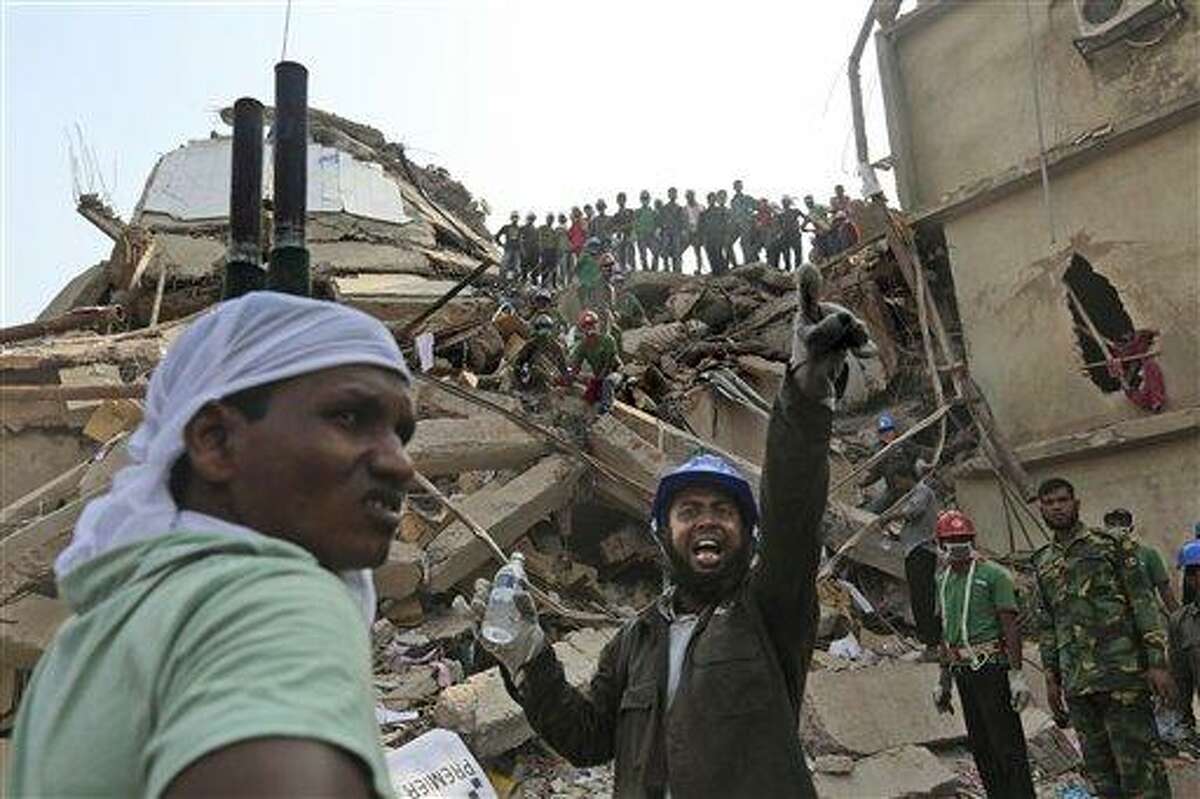 A Bangladeshi rescuer shouts for assistance as another waits with a stretcher fro injured or dead at the site of a building that collapsed Wednesday in Savar, near Dhaka, Bangladesh, Thursday, April 25, 2013. By Thursday, the death toll reached at least 194 people as rescuers continued to search for injured and missing, after a huge section of an eight-story building that housed several garment factories splintered into a pile of concrete. (AP Photo/Kevin Frayer)