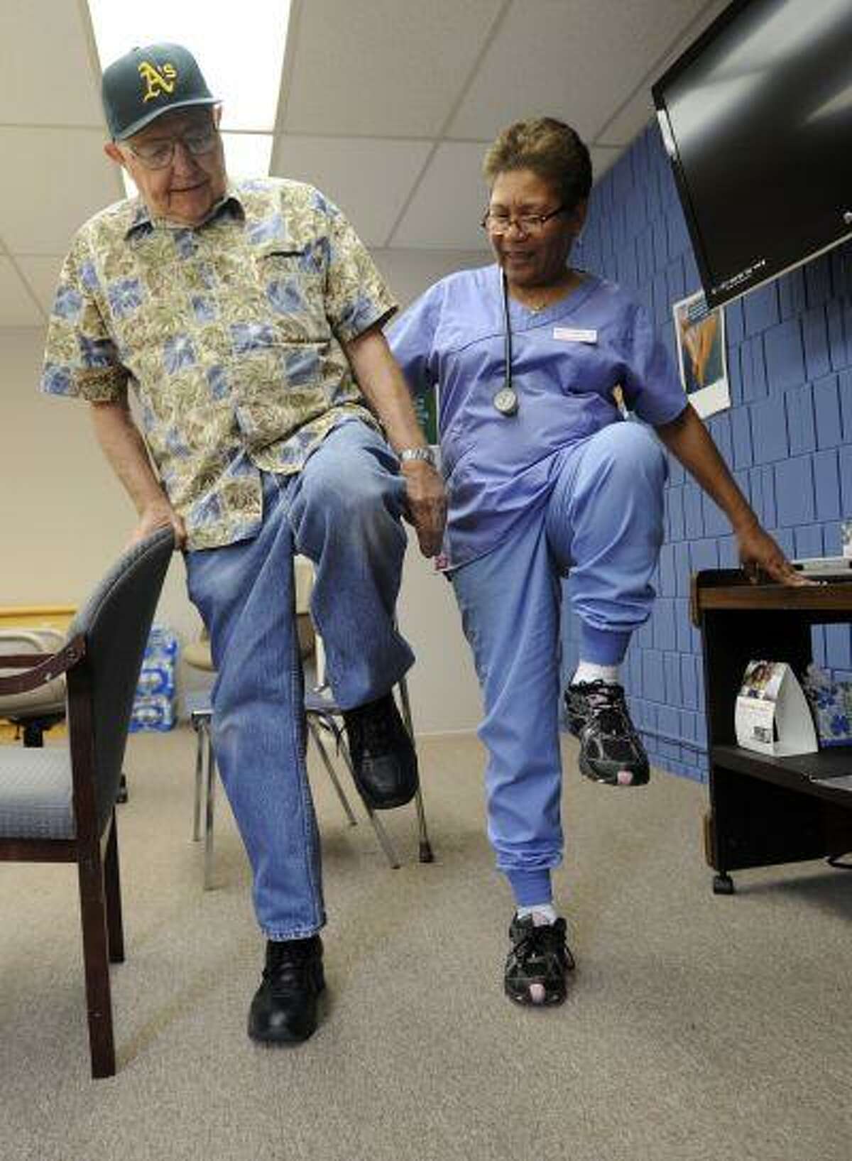 Rosita Gobbell, shows Blackie Blackwell, 87, leg lift exercises he can do to improve his strength and balance at the Meals on Wheels and Senior Outreach Services in Walnut Creek, Calif., on Monday, July 15, 2013.(Susan Tripp Pollard/Bay Area News Group)