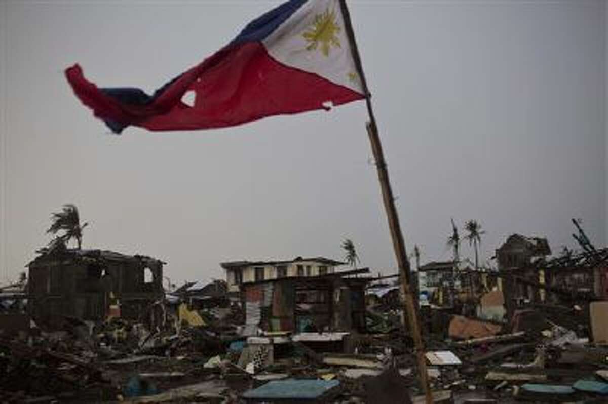 A flag of the Philippines flies over a destroyed neighborhood in Tacloban, Philippines on Friday Nov. 22, 2013.
