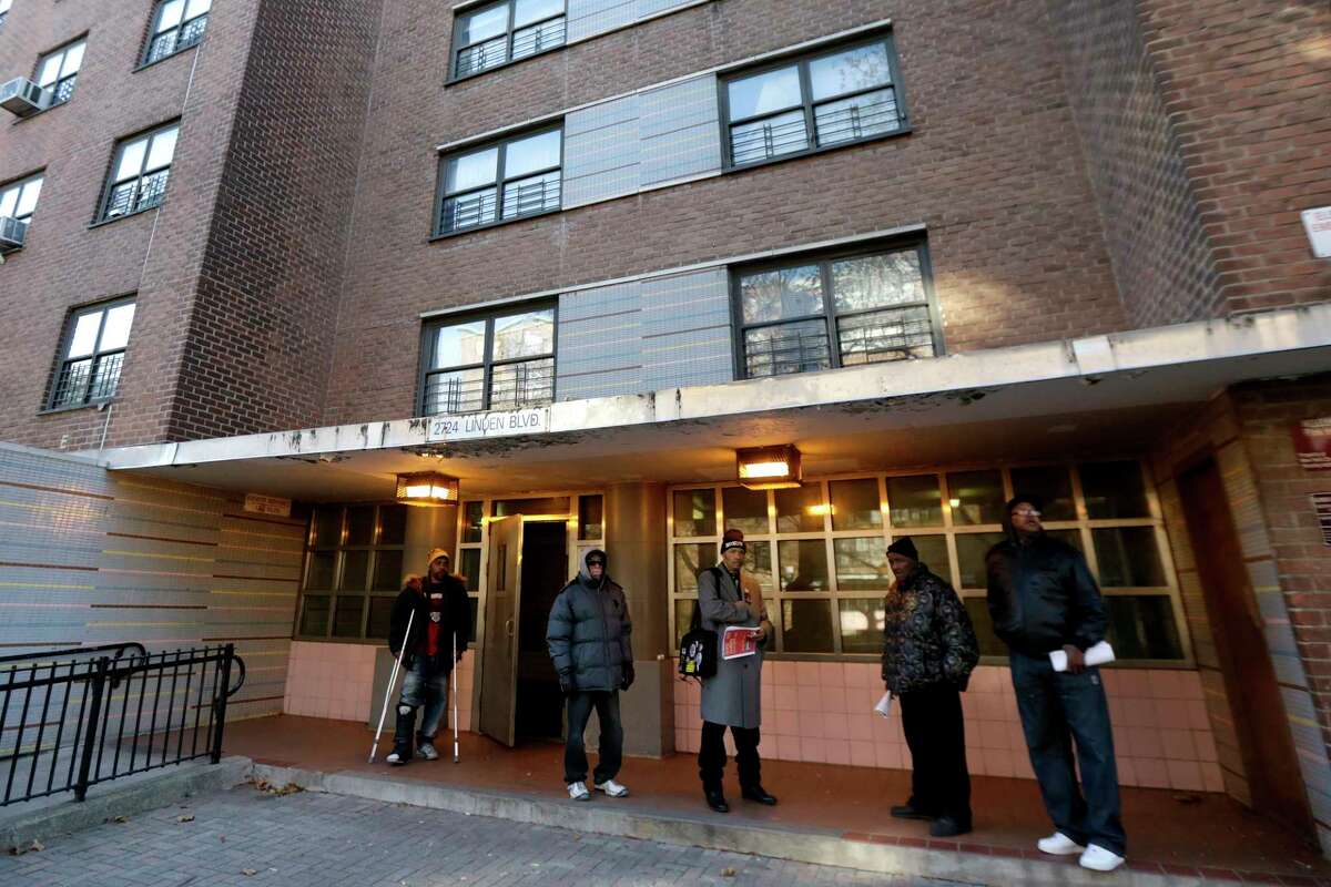 Men gather outside of the building where a man was allegedly shot by a police officer the night before at the Louis Pink Houses public housing complex, Friday, Nov. 21, 2014, in Brooklyn borough of New York. A rookie police officer with his gun drawn shot to death 28-year-old Akai Gurley, an unarmed, innocent man in the darkened stairwell of the crime-ridden public housing complex, New York City police officials said Friday. The shooting appeared to be an accident, Police Commissioner William Bratton said at a news conference. (AP Photo/Julio Cortez)